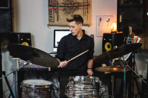 Luke Markham, a tenant at BQE Studios, practicing drums in the studio