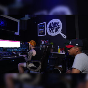 Two artists collaborating and recording audio in a music studio space